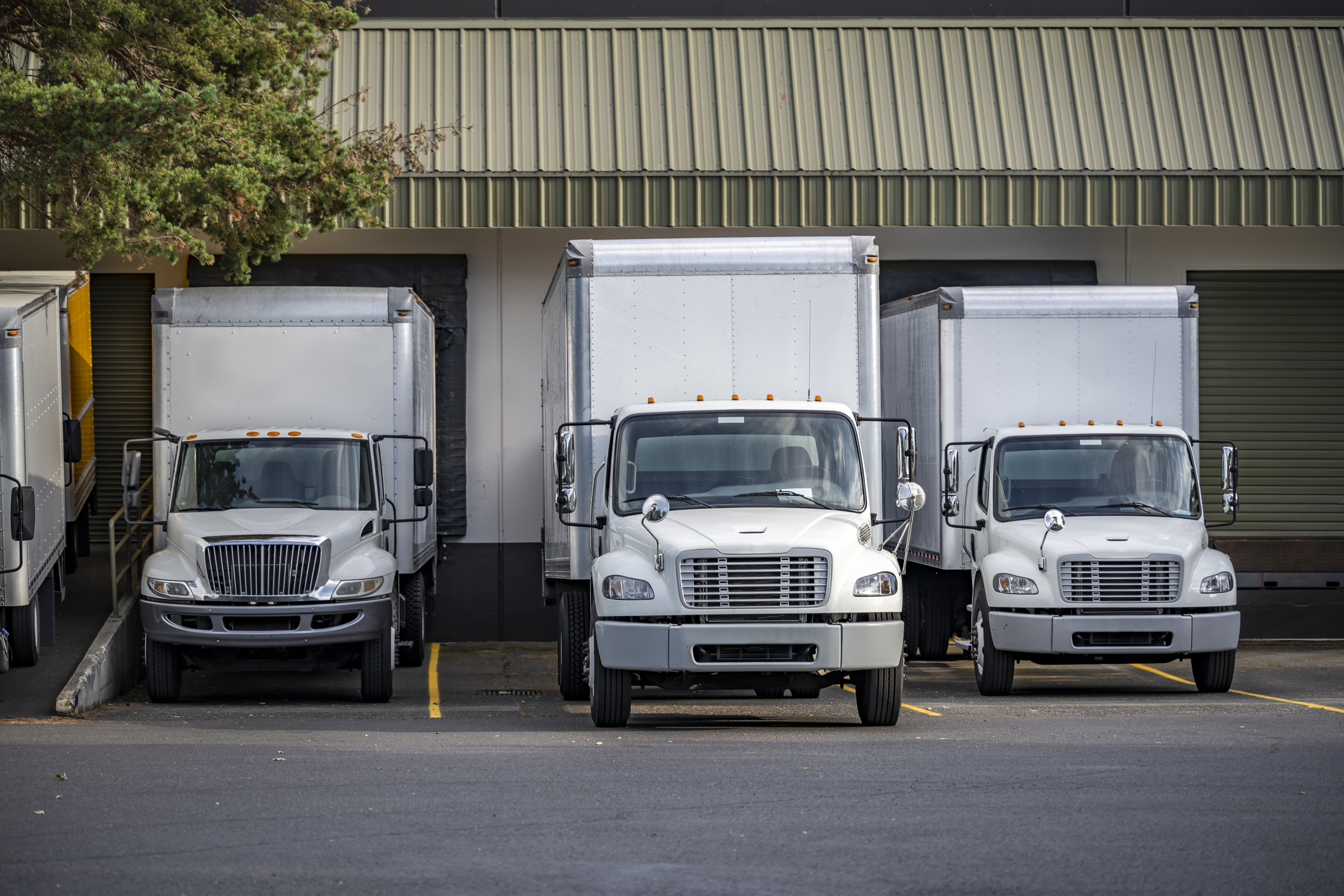 Useful Industrial standard for local deliveries and short haul freights compact middle duty rigs semi trucks with box trailers standing in warehouse dock with gates loading cargo for next delivery