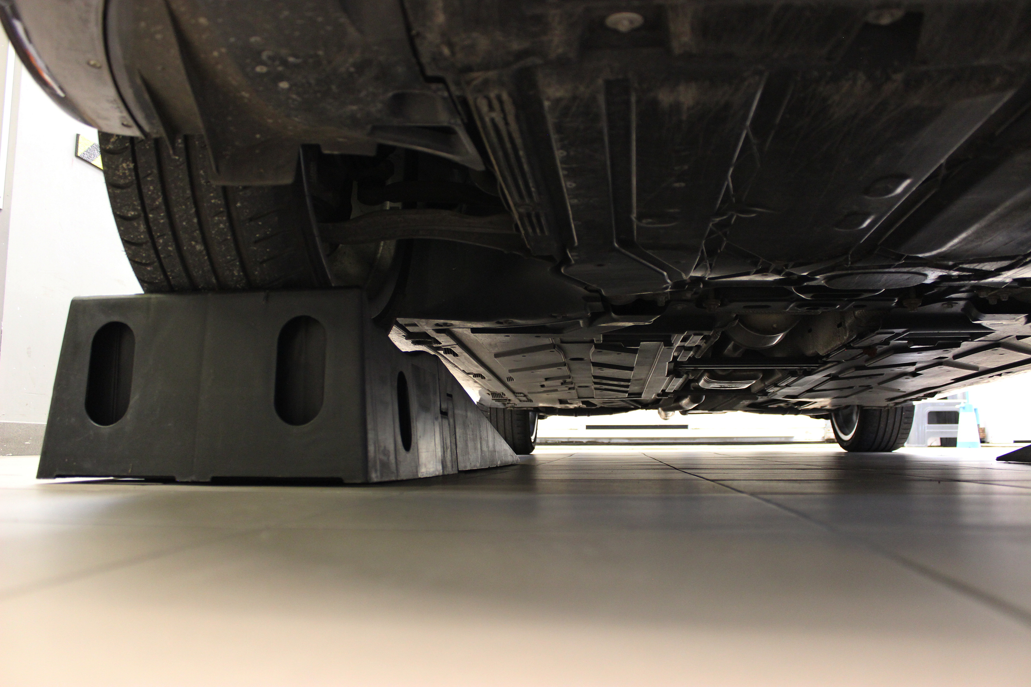 Engine crankcase guard is attached to the bottom of a car raised on special stoppers in a garage